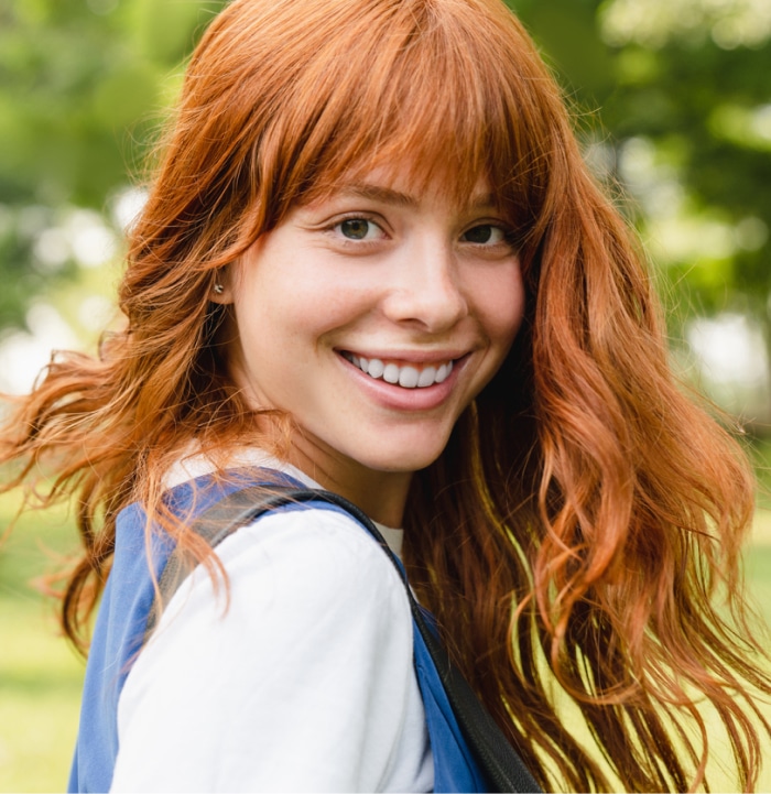 Red-head with long hair turning around outside.