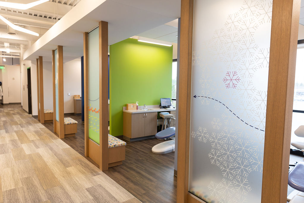 A modern dental clinic with colorful partitions, frosted glass designs, examination chairs, and bright decor, creating a welcoming and organized atmosphere.